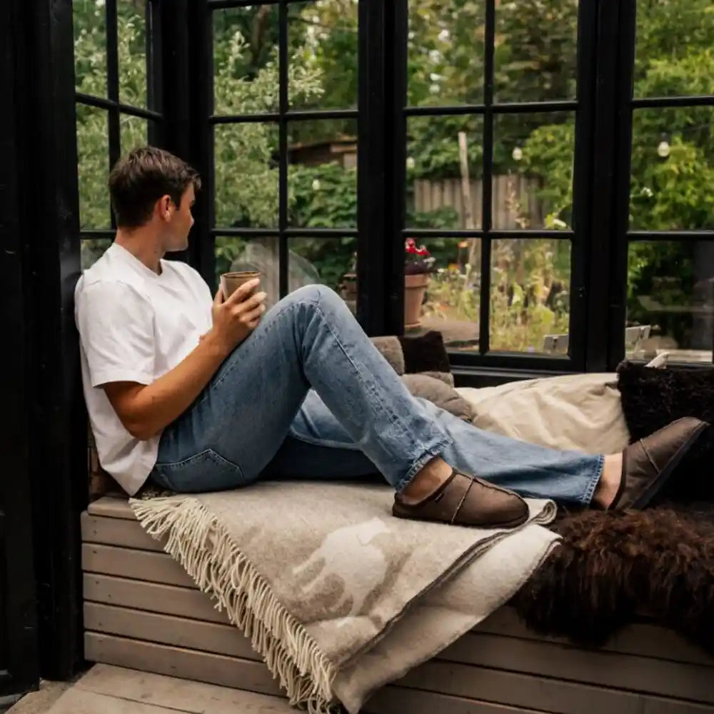 Person sitting on a window seat with a view of greenery outside